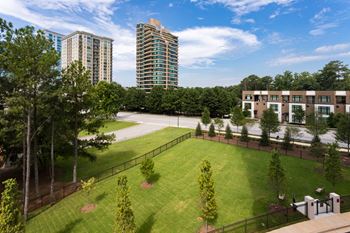 a grassy area with trees and buildings in the background